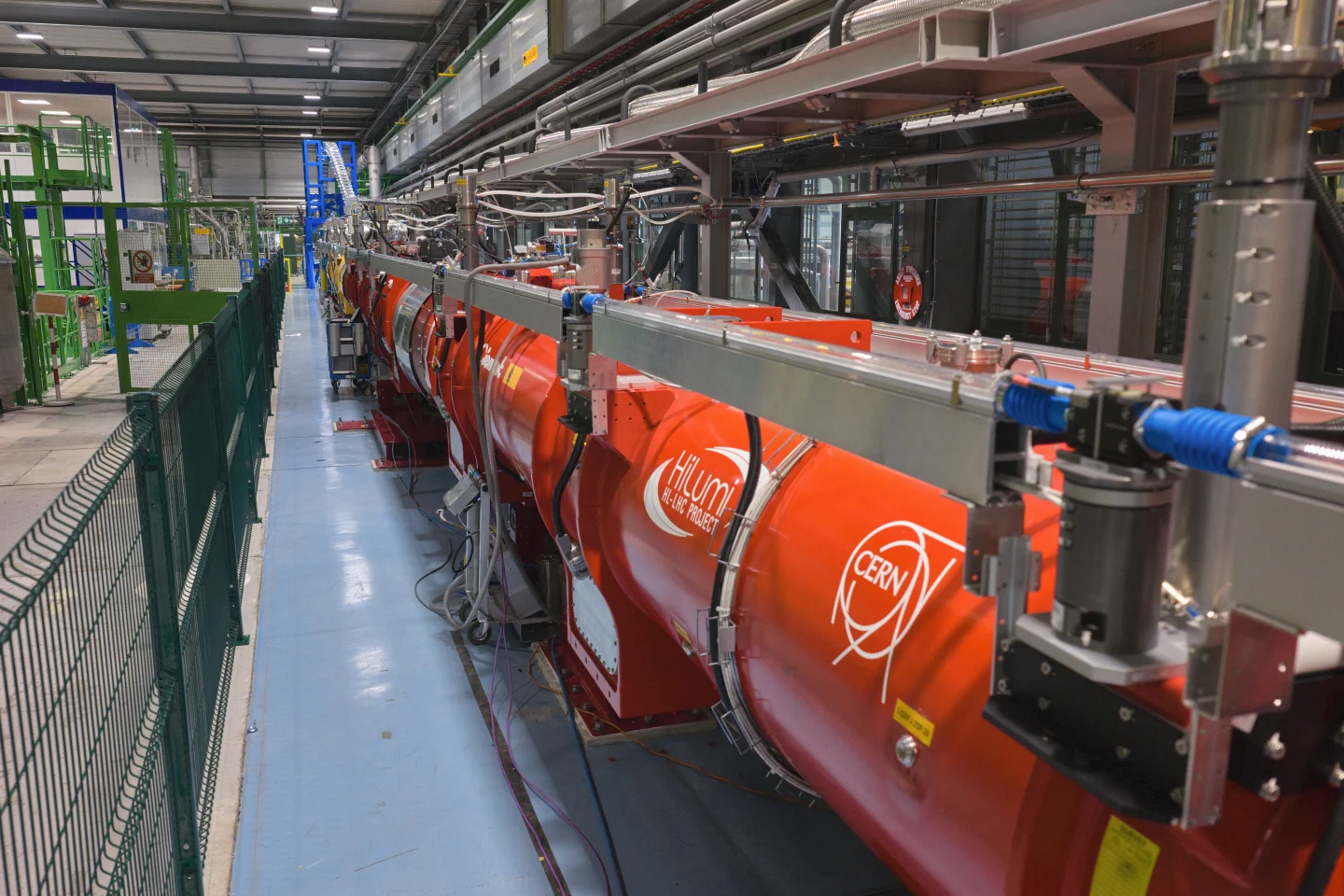 Uma sequência de grandes ímãs quadrupolos laranja do projeto HiLumi LHC instalada em uma bancada de testes do CERN.